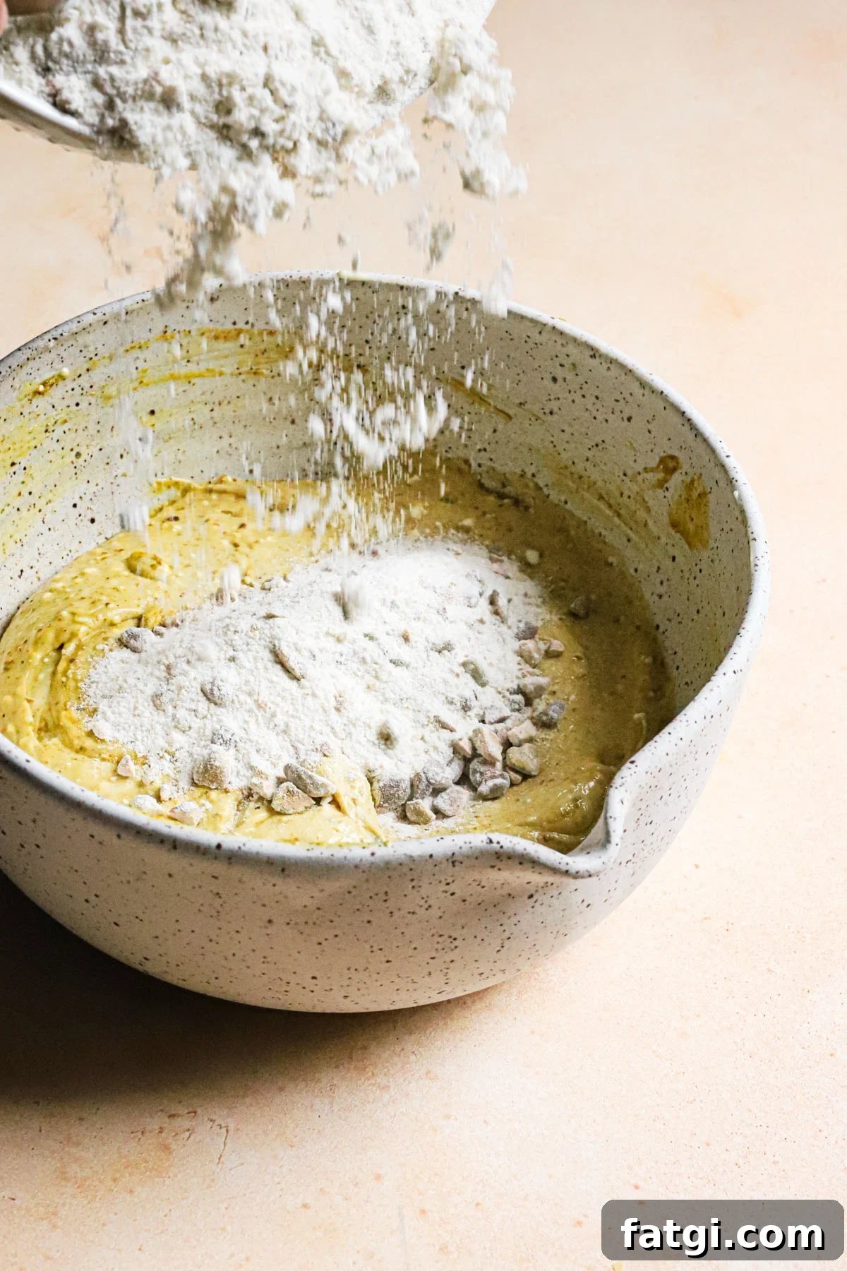 Double Pistachio Muffins with Cream Cheese Filling 7 Adding flour mixture to a bowl of muffin batter.