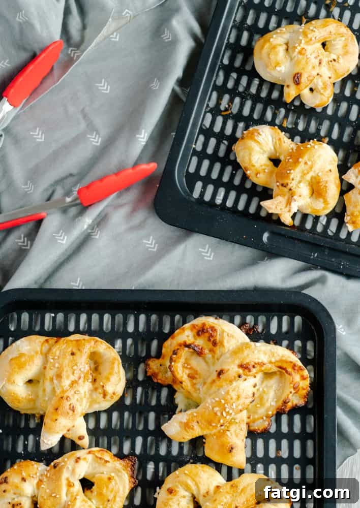 Air fryer pretzels resting on air fryer racks with tongs beside the racks.