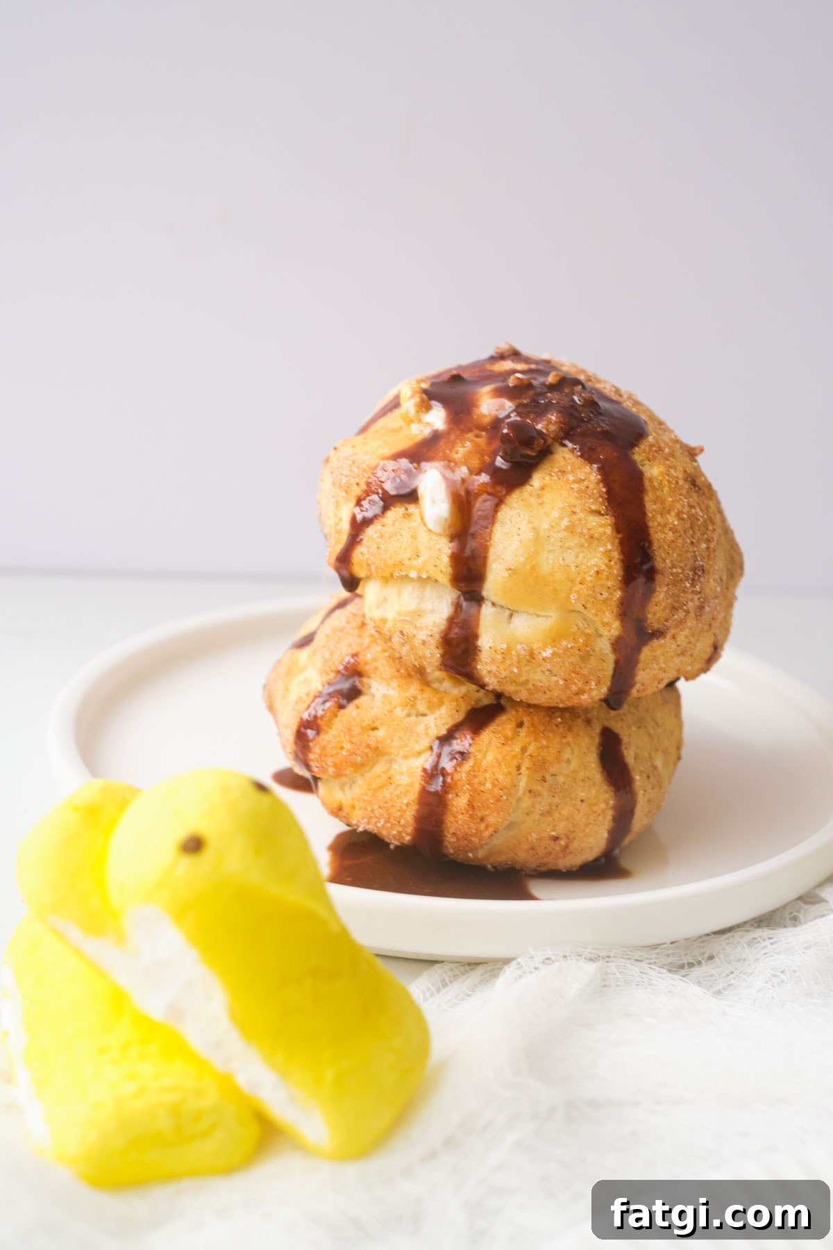 Air Fryer Peeps Crescent Rolls 2 two of the completed air fryer peeps rolls on a white plate with a yellow marshmallow peep sitting in front