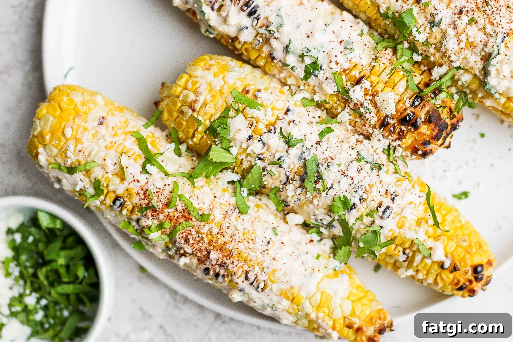mexican street corn on a white plate topped with cilantro and cotija