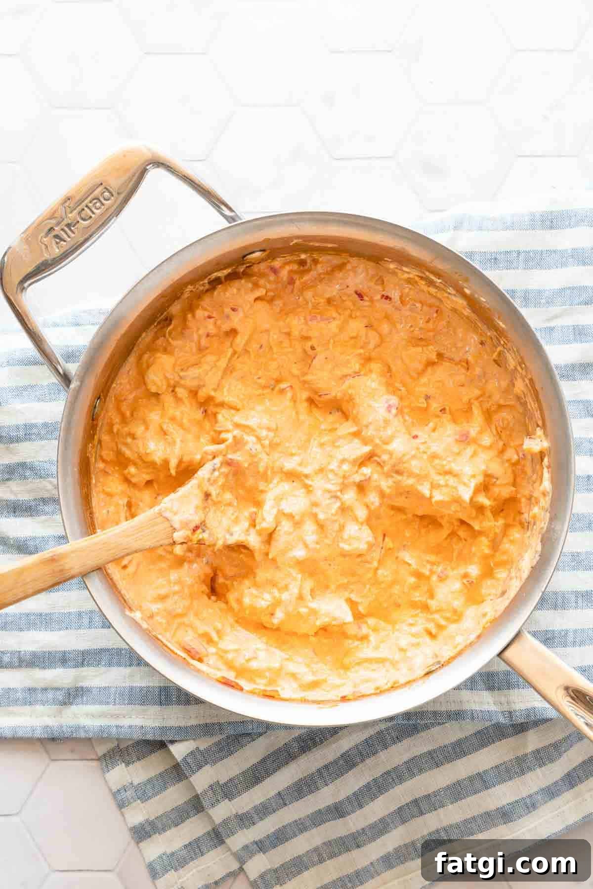 saucepan of buffalo chicken dip with wooden spoon inside the pan.