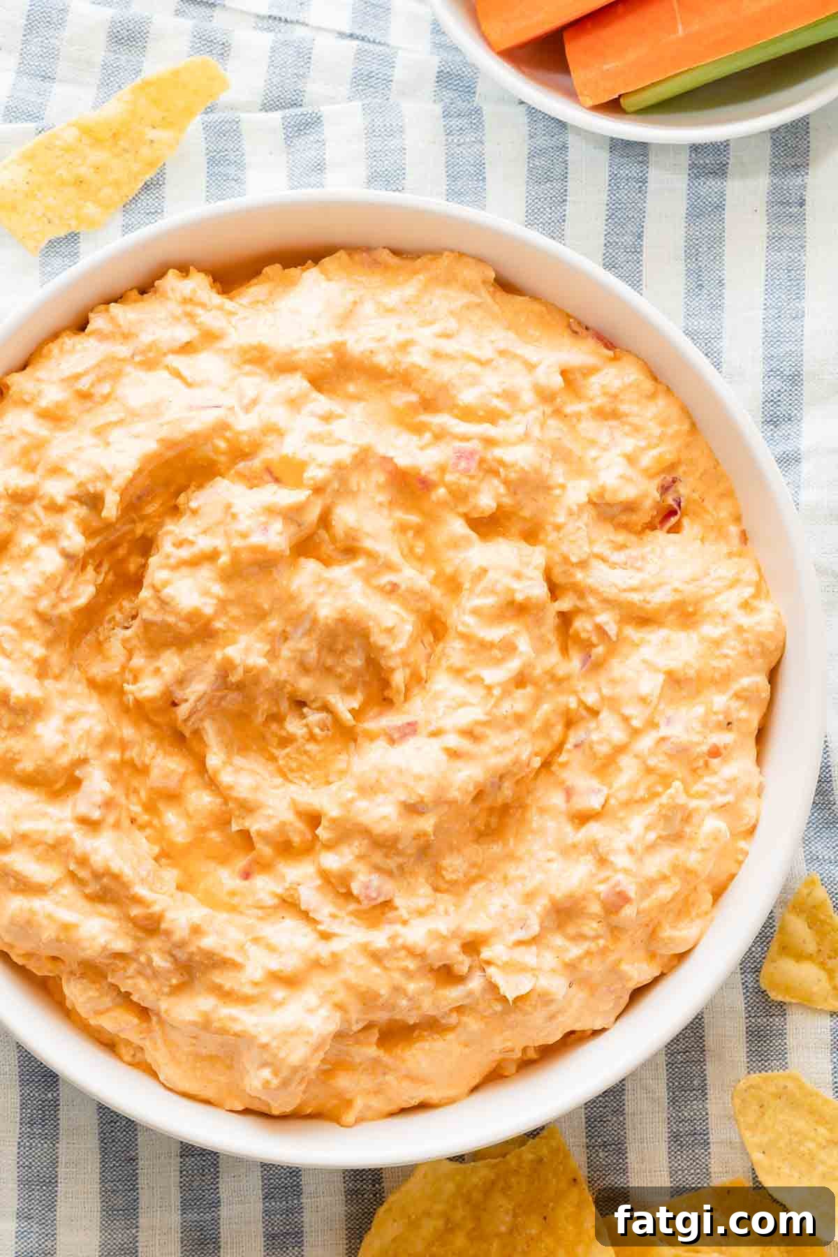 bowl of Greek yogurt buffalo chicken dip with chips and carrots on the side.