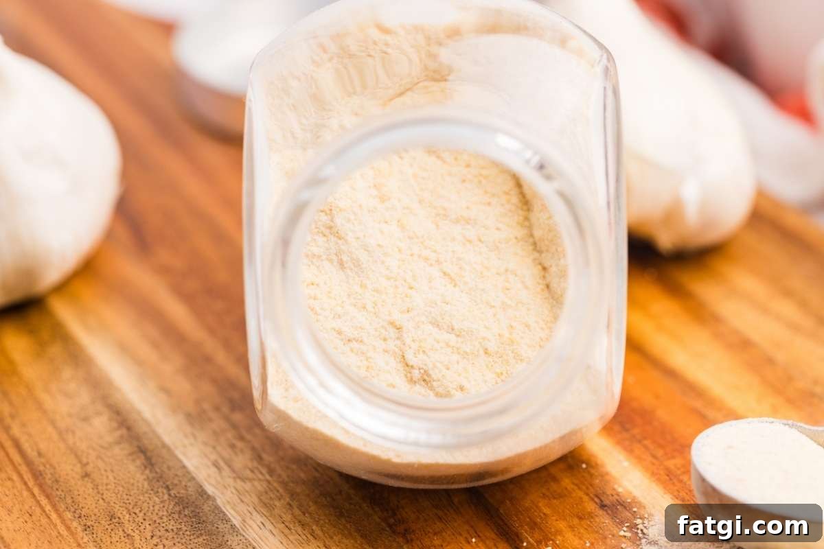 Make Garlic Powder at Home Using a Dehydrator 9 Spoon and jar of garlic powder on wooden board.