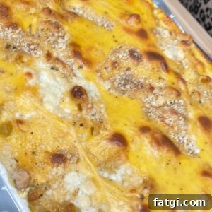 A close-up of a freshly baked macaroni and cheese casserole with a golden, crispy cheese and breadcrumb topping, resting on a foil-lined baking tray.